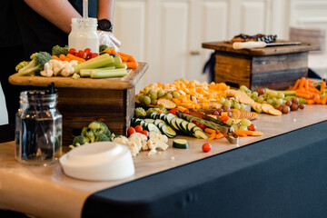 Buffet table with fresh vegetables, cheese, fruits, and dips.

