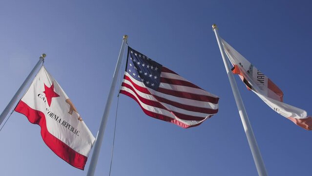 The flags of the USA and the California Republic are flying proudly in the clear blue sky
