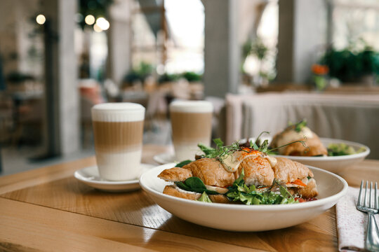 croissant sandwiches and coffee cups on wooden table