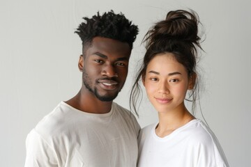Fototapeta premium Portrait of a glad multiethnic couple in their 20s dressed in a casual t-shirt isolated in minimalist or empty room background
