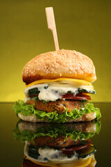 Delicious vegetarian burger on mirror surface against olive background