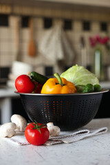 Metal colander with different wet vegetables on white textured table, closeup