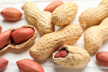 Fresh unpeeled peanuts on white wooden table, closeup