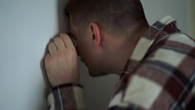 the man checks who is behind the door.
A man looks through the door peephole.
A man stands at the front door and looks through the peephole