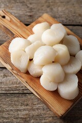 Board with fresh raw scallops on wooden table