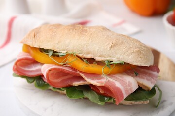 Tasty sandwich with bacon and bell pepper on white table, closeup