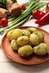 Tasty young boiled potatoes with dill and other products on wooden table
