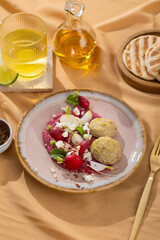 Healthy raw summer vegan snack plate. Flat-lay of beetroot humus dip with falafel and colorful fresh vegetables and greens on pink table background, top view. Clean eating, dieting, vegan