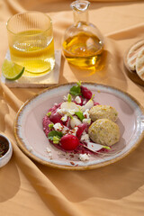 Healthy raw summer vegan snack plate. Flat-lay of beetroot humus dip with falafel and colorful fresh vegetables and greens on pink table background, top view. Clean eating, dieting, vegan