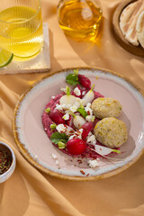 Healthy raw summer vegan snack plate. Flat-lay of beetroot humus dip with falafel and colorful fresh vegetables and greens on pink table background, top view. Clean eating, dieting, vegan