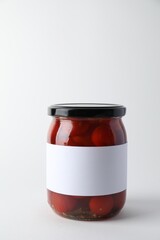 Tasty pickled tomatoes in jar on light background