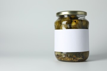 Pickled cucumbers in jar on light background. Space for text