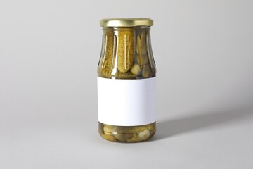 Pickled cucumbers in jar on light background