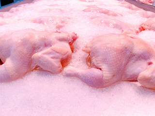 Fresh frozen whole chickens covered in ice in the market meat section