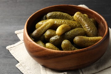 Pickled cucumbers in bowl on grey wooden table, closeup