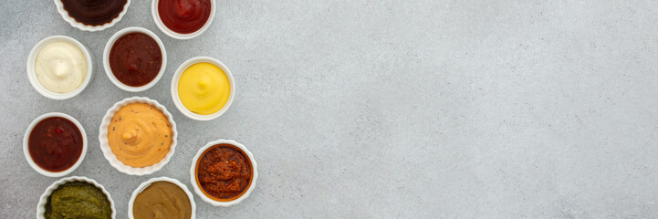 Different types of sauces in bowls banner, ketchup and mayonnaise, pesto and mustard, cheese sauce, top view, copy space