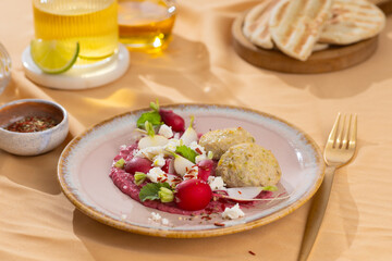 Healthy raw summer vegan snack plate. Flat-lay of beetroot humus dip with falafel and colorful fresh vegetables and greens on pink table background, top view. Clean eating, dieting, vegan