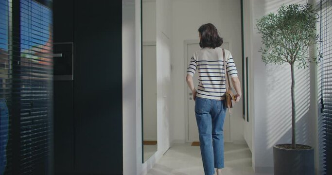 Charming Caucasian girl coming up close to mirror. Checking look and clothing. Wearing sweater, jeans and high heels. Carrying small purse on shoulder. Going on date. Ready for positive evening.