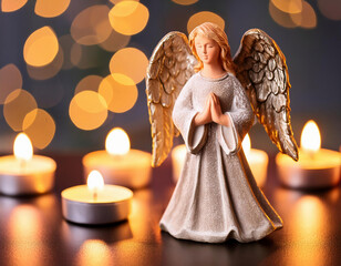 An angel figurine surrounded by flickering tealights and blurred, sparkling bokeh lights.