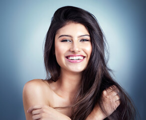 Naklejka premium Woman, portrait and smile in studio for hair care, hairdresser and beauty salon on blue background. Girl, happy and confidence with healthy texture, wellness and treatment with growth transformation