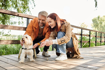 An adult loving couple in casual attire pet a small dog while taking a walk in the park.