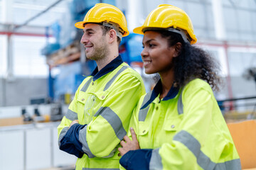 Male and female engineers in neat work clothes prepare and control the production system of large modern machines in a factory producing industrial technology products.