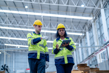 Male and female engineers in neat work clothes prepare and control the production system of large modern machines in a factory producing industrial technology products.