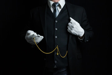 Portrait of Butler or Hotel Concierge in Dark Suit and White Gloves Holding Pocket Watch. Vintage Style and Retro Fashion.