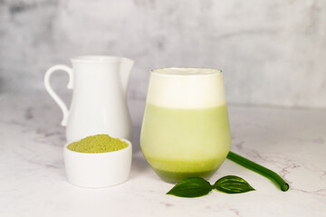 Refreshing matcha latte with powder or matcha with milk placed on white marble surface.  