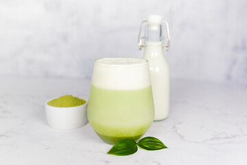Refreshing matcha latte with powder or matcha with milk placed on white marble surface.  