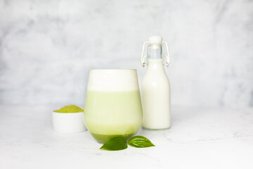 Refreshing matcha latte with powder or matcha with milk placed on white marble surface.  