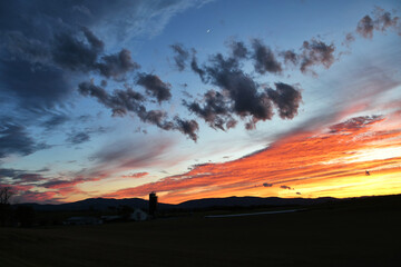 Sunset across farmland with mountains and vivid clouds