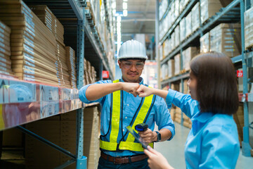 Two people in a warehouse, one wearing a hard hat and the other holding a tablet. They are shaking hands