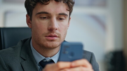 Serious manager looking cellphone screen sitting modern office workplace closeup