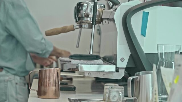 barista holding pitcher making coffee at coffee shop with coffee machine