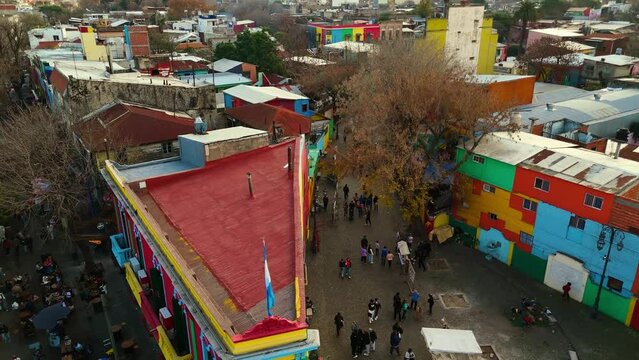 Traditional Caminito passage with tourists and panoramic view of the city from La Boca neighborhood. Aerial camera rises from the street