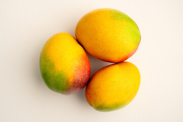 three mangos lying together on a white background