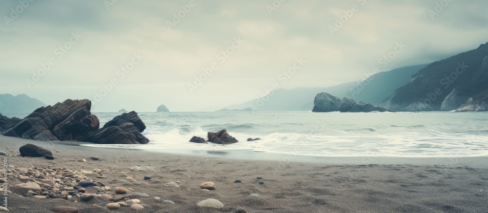 Poster Boulders and stones line the shoreline of a vast ocean in a stunning seascape view. with copy space image. Place for adding text or design