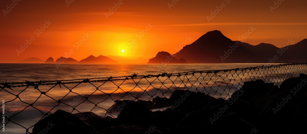 Aufkleber Sunset hues over the ocean captured through a chain link fence, adding a unique perspective to the scene. with copy space image. Place for adding text or design