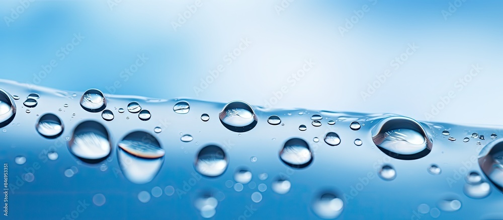 Poster macro capture of water droplets glistening on glass against a blurred blue sky background. with copy