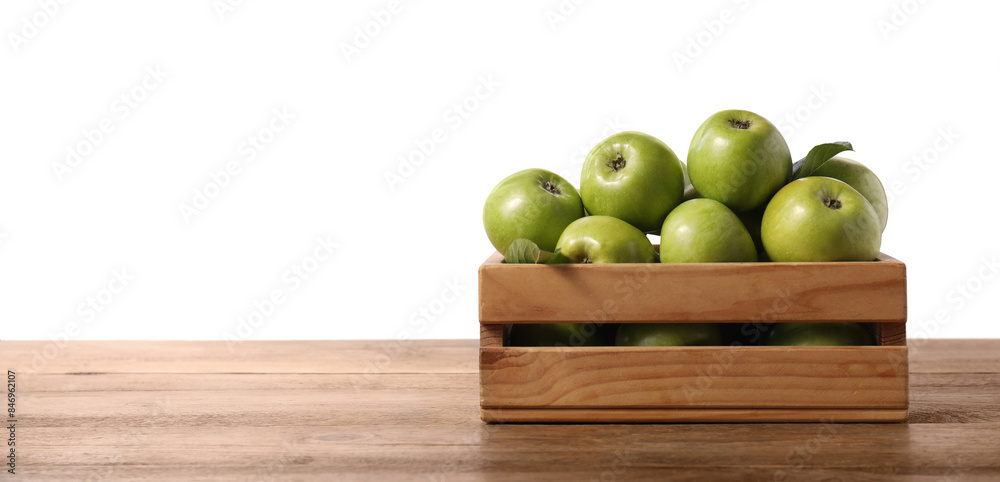 Wall mural Ripe green apples in crate on wooden table against white background. Space for text