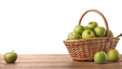 Ripe green apples in wicker basket on wooden table against white background. Space for text
