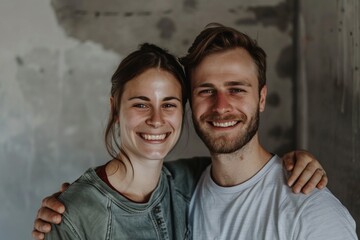 Portrait of a glad caucasian couple in their 20s wearing a simple cotton shirt in front of empty modern loft background