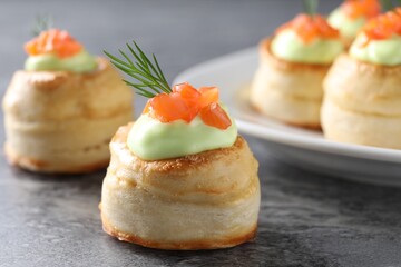 Delicious puff pastry with avocado cream, salmon and dill on grey table