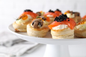 Different delicious puff pastry snacks on stand, closeup