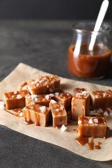 Tasty candies, caramel sauce and salt on grey table, closeup