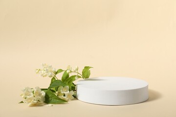 Presentation of product. White podium and beautiful jasmine flowers on beige background, space for text