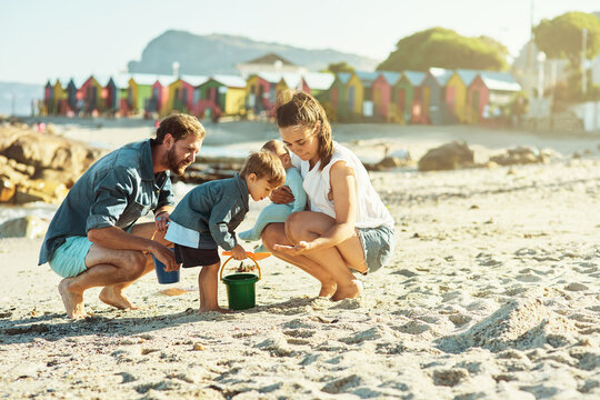 Sunshine, beach and boy with parents, sand and weekend break with vacation, getaway trip and adventure. Happy family, mother and father with son, seaside and toys with holiday, summer and journey