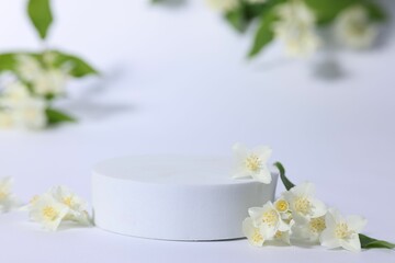 Presentation of product. Podium and beautiful jasmine flowers on white background