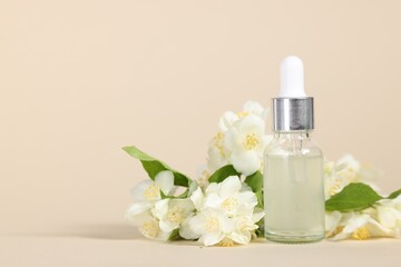 Essential oil in bottle and beautiful jasmine flowers on beige background, space for text